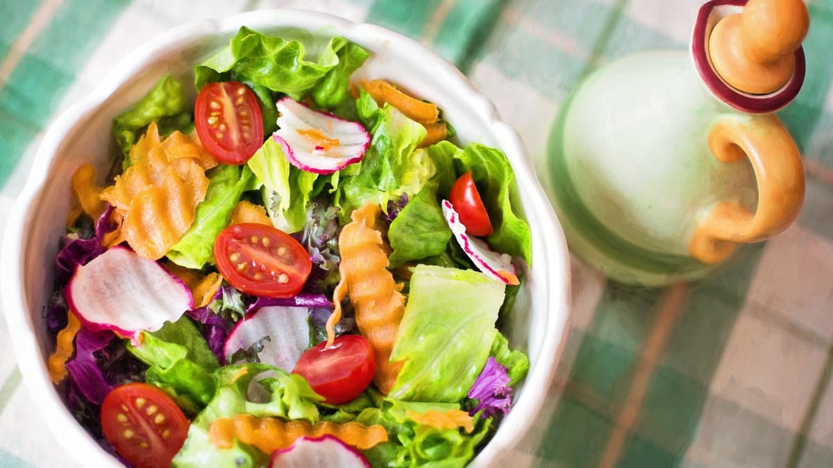 Colorful fresh vegetable salad with cherry tomatoes in a white bowl.